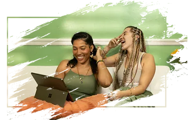 Two happy women enjoying looking looking at a website on a laptop.